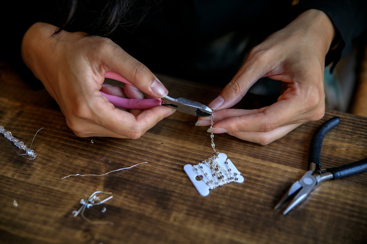 Detailed view of hands crafting jewelry using pliers, showcasing creativity and craftsmanship.